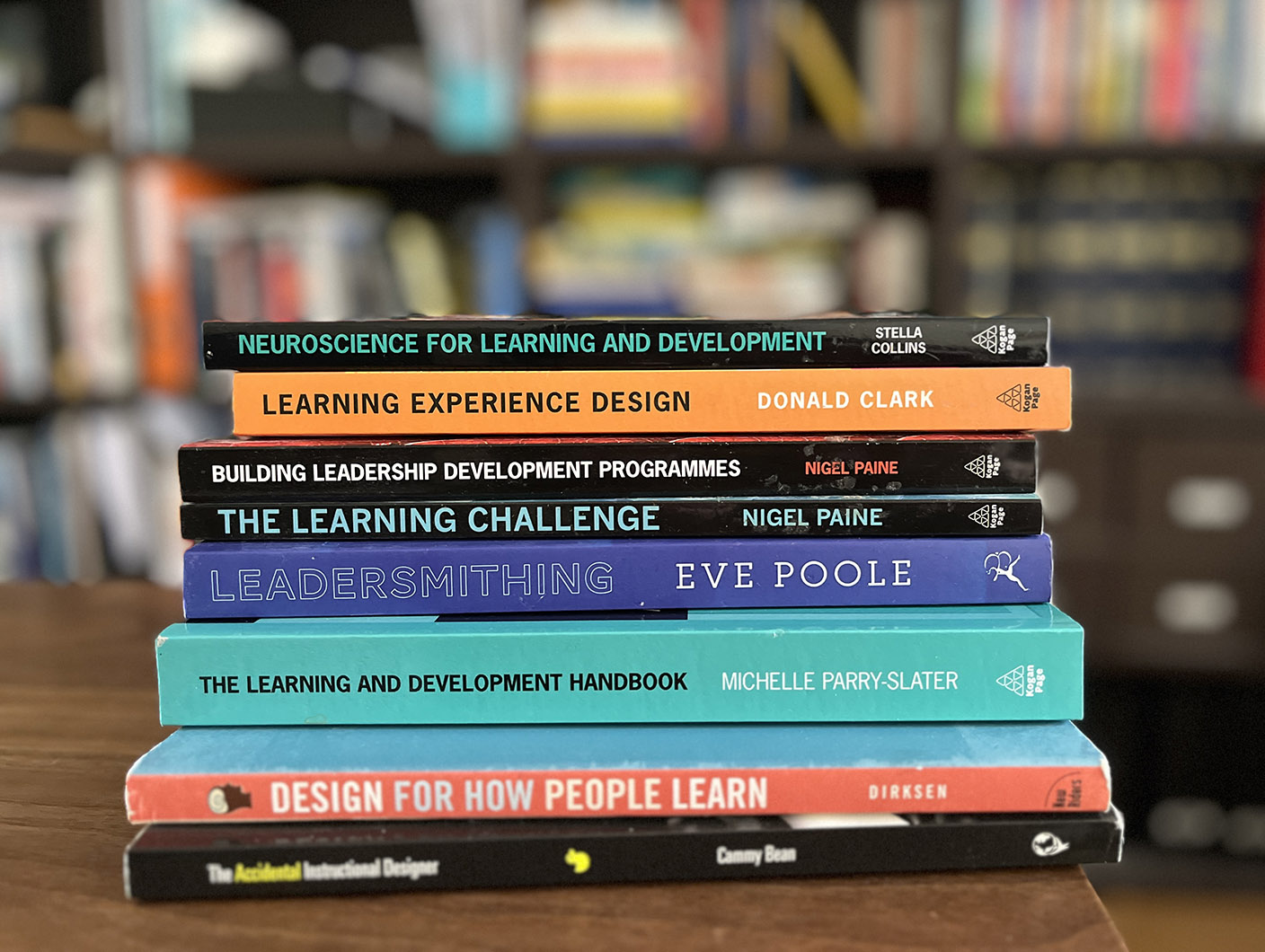 Stack of different coloured books about adult learning, laid horizontally on a table