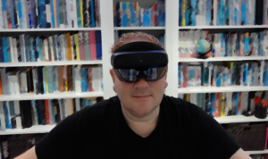 Richard Price, director of technology at the Learning Technology sits in front of a stylised bookcase, wearing a virtual reality headset.